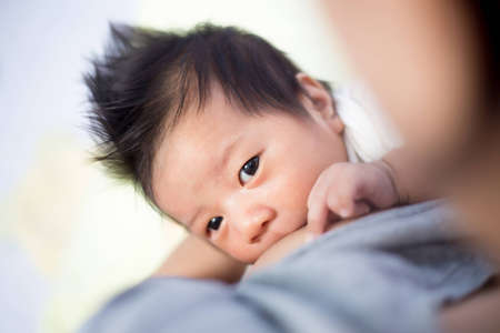 Young mother breastfeeding the newborm baby - indoorsの写真素材