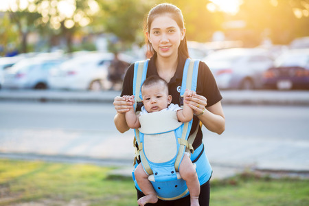 Baby boy riding in infant carrier by mother outdoorsの写真素材