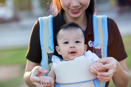 Young mother with her toddler child in a baby carrierの写真素材