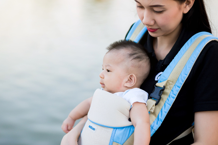 Young mother with her toddler child in a baby carrierの写真素材