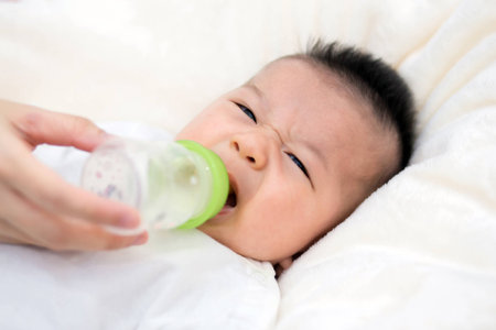 beautiful mother feeding baby boy with a milk bottle at homeの写真素材
