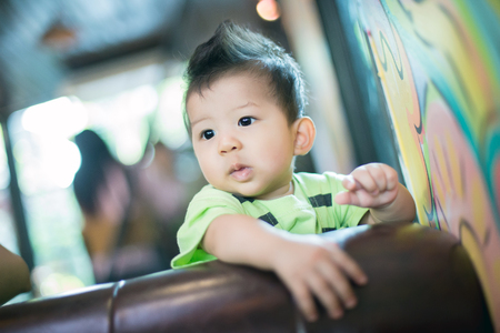 Adorable baby boy sitting on a sofa.の写真素材