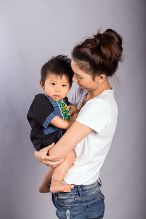 Happy beautiful mother holds her adorable baby. Studio shot.の写真素材