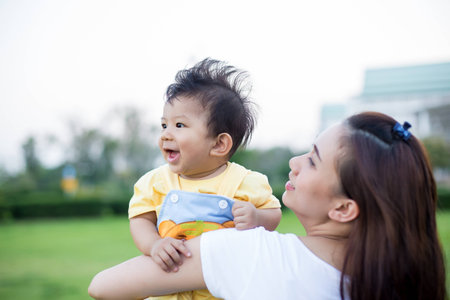 Cheerful mother holding her son at sunset