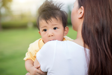 Young mother relaxing with her little son in spring garden.の写真素材