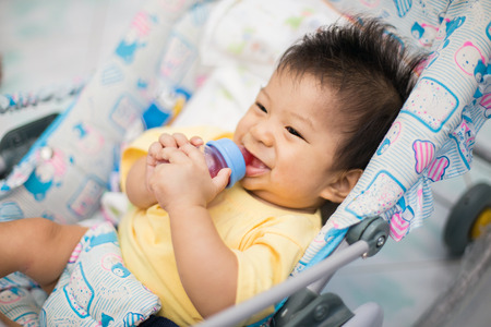 Beautiful little baby with a milk bottle in bedの写真素材
