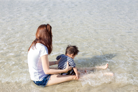 Mother and baby playing with sea wavesの写真素材