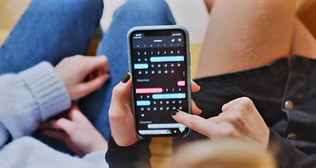 Close-up of female hands using mobile phone with app on screenの写真素材