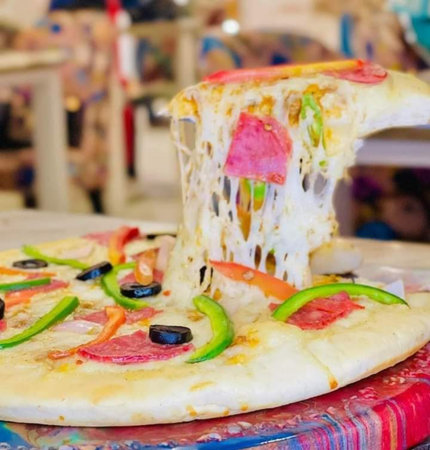 Pizza with olives and tomato on the table in a restaurantの写真素材