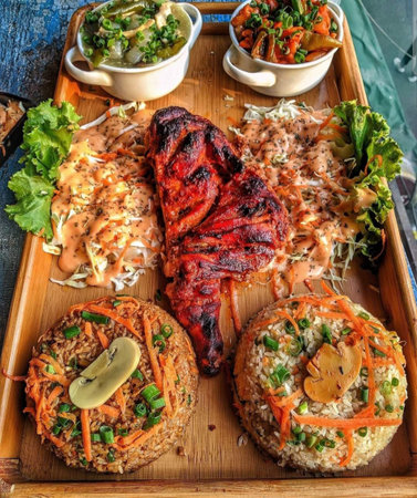 Grilled pork ribs with rice and vegetables on a wooden plate.