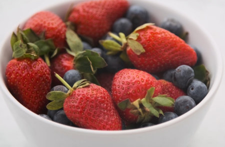 Strawberries and blueberries in a bowl on a white backgroundの写真素材