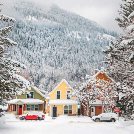 Beautiful houses in the snowy mountains. Winter landscape. Car on the road.