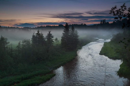 Sunset over the river in the forest with fog in the foreground