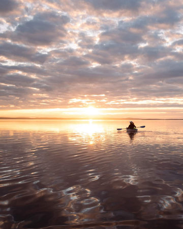Silhouette of a man on a stand up paddle board at sunsetの写真素材