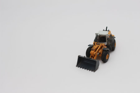 a close up of miniature orange wheel loader toy isolated on white background. concept photo of heavy...
