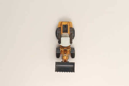 a close up of miniature orange wheel loader toy isolated on white background. concept photo of heavy equipment miniature toy.の写真素材