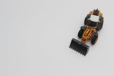 a close up of miniature orange wheel loader toy isolated on white background. concept photo of heavy...