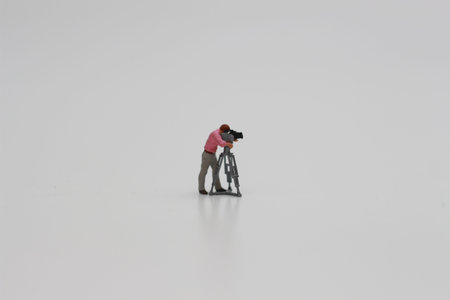 a close up of miniature figure of a videographer isolated on white background. Miniature figure...