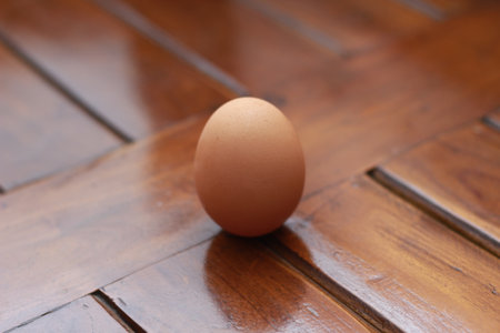 a close up of a chicken egg isolated on a natural patterned wooden background. healthy food ingredients photo concept.の写真素材