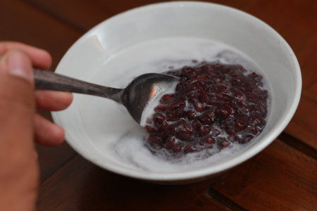 a close up of a bowl of black sticky rice porridge with coconut milk ready to eat. Indonesian traditional food concept.の写真素材