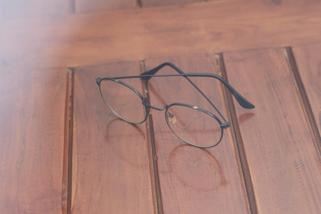 a close up of eyeglasses with black frames isolated natural patterned wooden background.