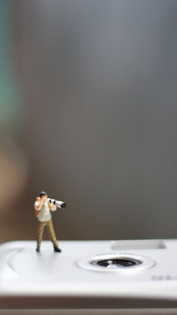 a miniature figure taking picture with a camera against a real camera in the background.の写真素材