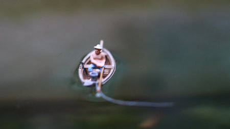 miniature figure of a fisherman fishing on a lake in a small boat.の写真素材