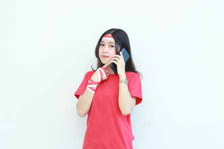 portrait of beautiful asian woman wearing red outfit celebrating Indonesia independence day while calling with a thinking expression isolated on white background.の写真素材