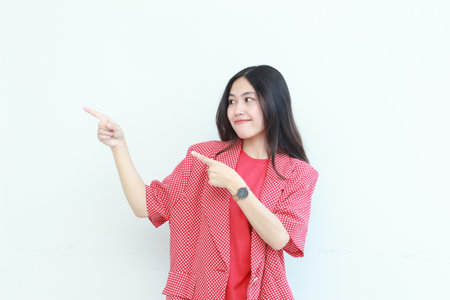 portrait of beautiful asian woman wearing red outfit pointing to the side for copy space isolated on white background.の写真素材