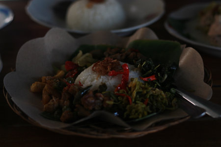 mixed rice containing sauteed papaya flowers, tempeh, intestines, cassava leaves and pumpkin. served on banana leaves.の写真素材