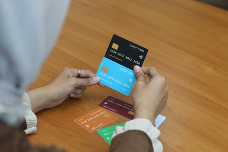 A woman carefully reviews credit cards, considering financial options. Online banking and secure...