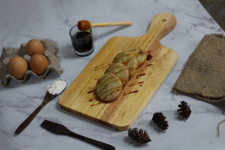 A tempting image of four serabi pancakes drizzled with honey, accompanied by eggs and flour on a...
