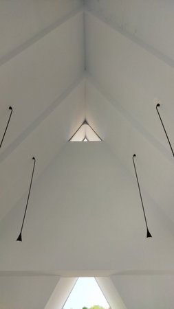 A sleek modern ceiling features a triangular skylight and four hanging pendant lights creating a bright, airy, and minimalist atmosphere ideal for contemporary interior design.の写真素材