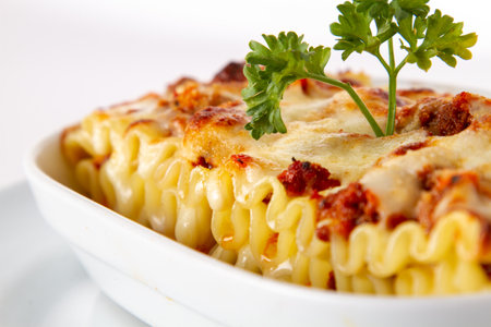Pasta with meat and cheese in a white plate on a white backgroundの写真素材