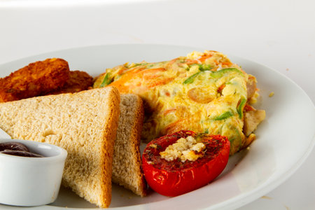 Breakfast with omelet, bread and vegetables on white backgroundの写真素材