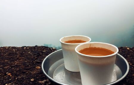 Steel tray with two white paper Tea cups kept on the wall during monsoon on a rainy day, in the background is the valley near Tamhini ghat in Maharashtra.の写真素材