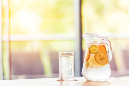 the fruit in the water and ice is on the table. the water in glass near jar.の写真素材
