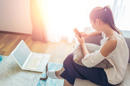 The women check phone and working in laptop in the room. the laptop is on the table.の写真素材
