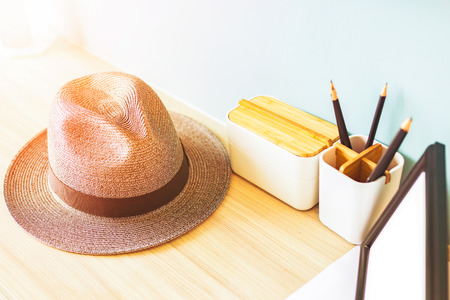 hat and pencil case are on the wood table. The empty picture frame is on the table.の写真素材