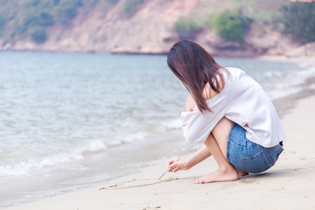 The women writing heart on sand on the beachの写真素材
