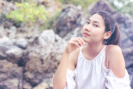 Beautiful women thinking and rocks background she smile and finger touch face and wear white dressの写真素材