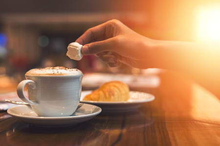 hands hold cup of coffee and spoon in the dish.の写真素材