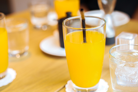 The orange juice in glass on the table near water ice.の写真素材