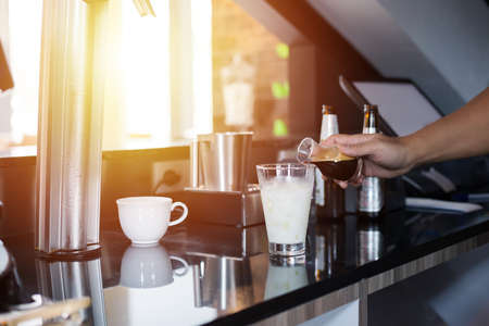 the barista make ice coffee and milk in the cup.の写真素材
