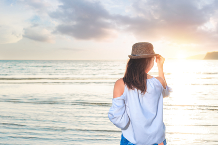 women stand on the beach and sea water between sunset and nice cloud.の写真素材