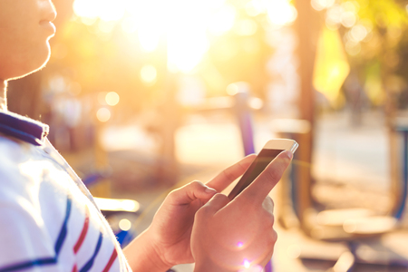 a man check mobile phone and light sunset with blur background.の写真素材
