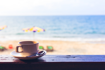 hot cup of coffee on the wood near the beach.の写真素材