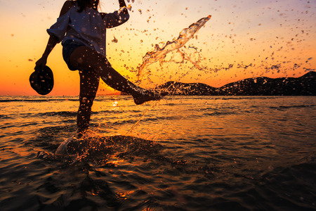 the women play water splash on the beach between sunsetの写真素材