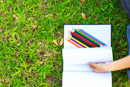 hand open white paper draw and crayon are on the paper.The  white paper is on the grass.の写真素材