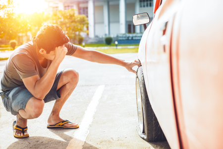 A man headache when car breakdown and wheel flat tire on the road in the city.の写真素材